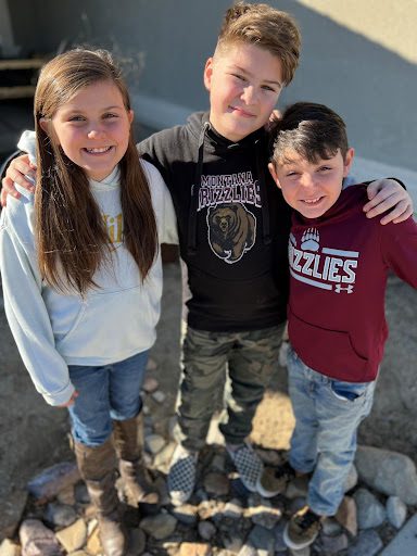 Three kids standing on some rocks.