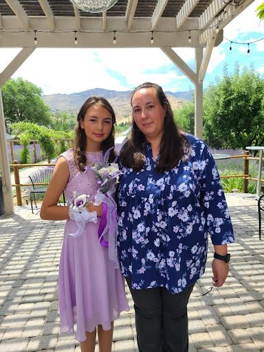 A woman and her daughter dressed up and standing on a patio.