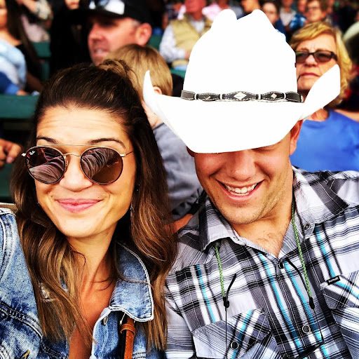 A woman in sunglasses poses with a man in a white cowboy hat.